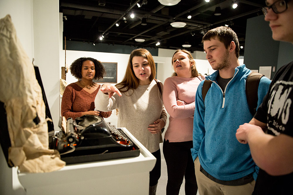 College students looking at typewriter